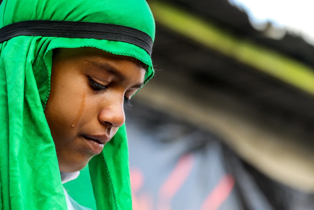 Foto de enfoque selectivo de una niña llorando con hiyab verde