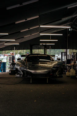 Close-up of a mechanic using diagnostic tools on a high-performance engine in a sleek, race-inspired garage.