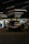 A male automotive influencer reviewing car parts in a well-lit garage setting.