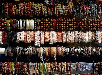Close-up of colorful mineral rock bracelets laid out beside patriotic hats on a rustic wooden table.