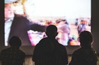 silhouette of 3 people watching show on TV