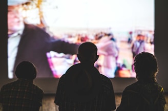 A group of friends watching a movie on a large screen in a living room.