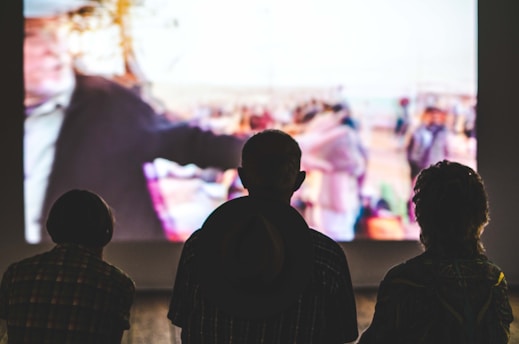A group of friends watching a movie on a large screen in a living room.