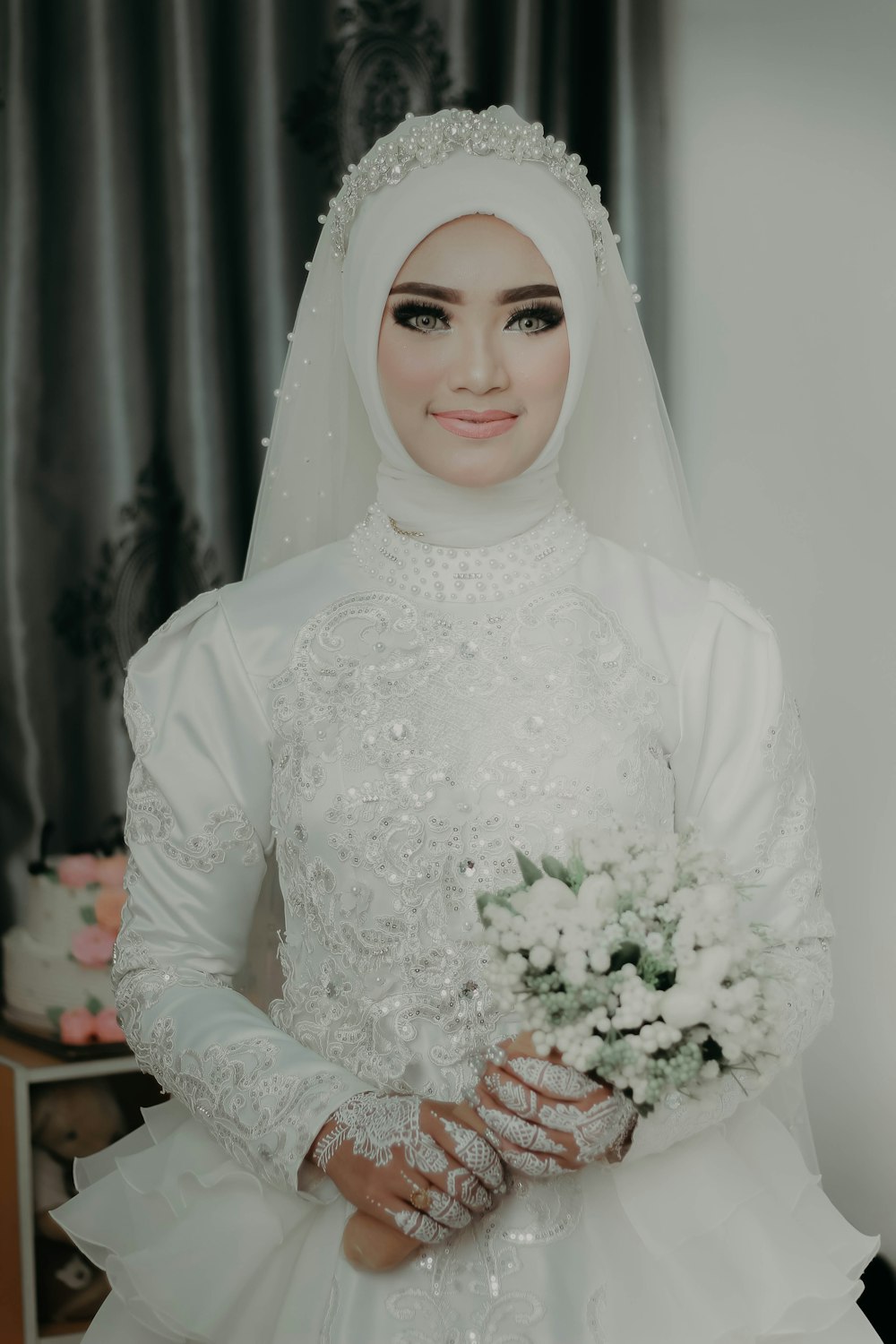 woman wearing abaya robe holding white bouquet of flowers