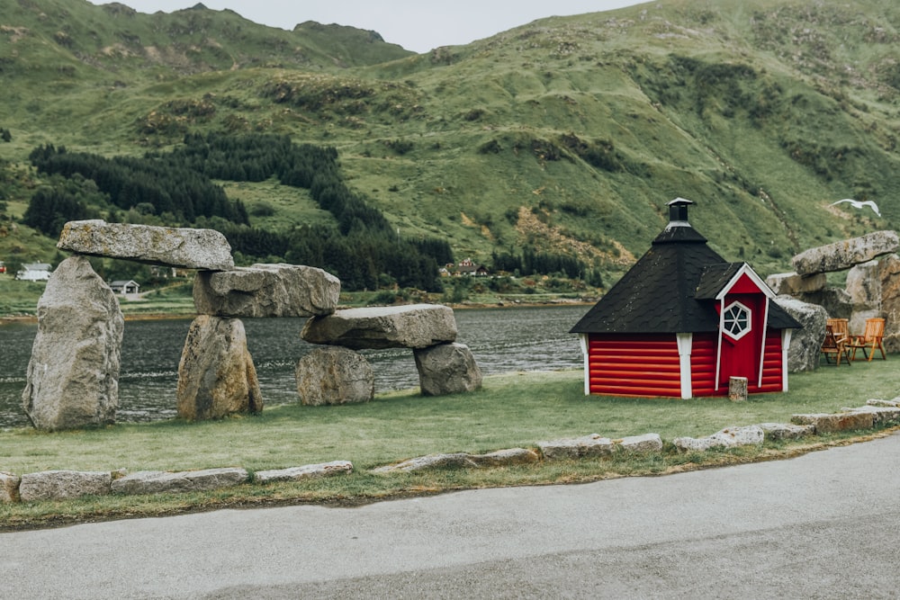 red and black wooden house beside rock formation