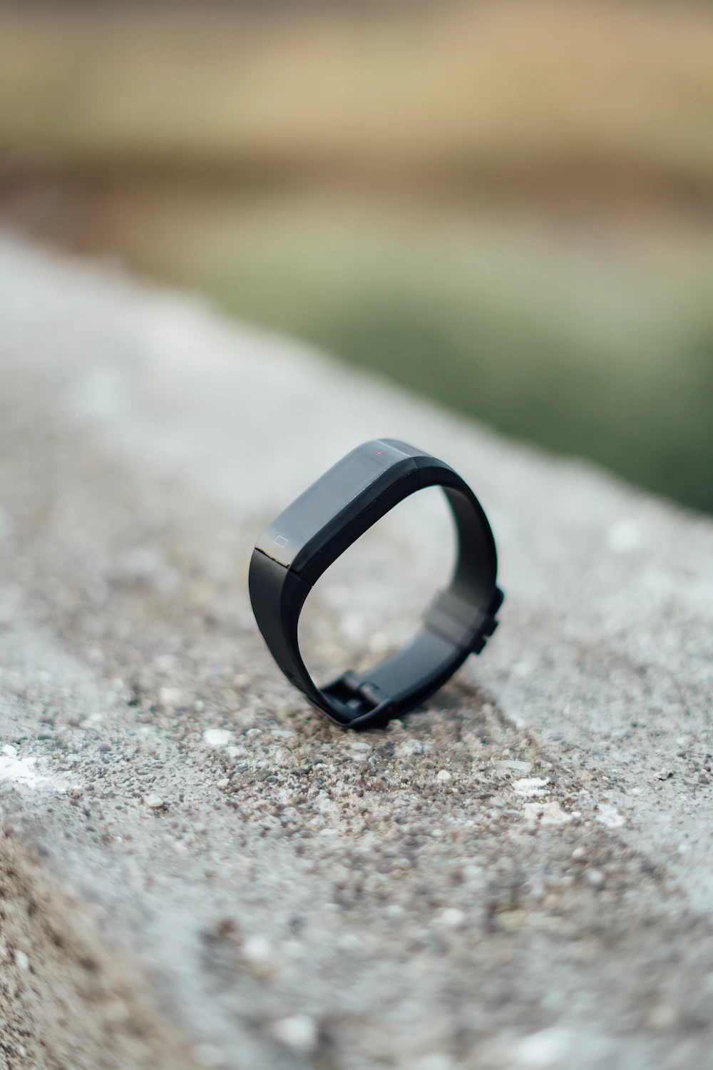 Slim black fitness tracker band on a stone ledge
