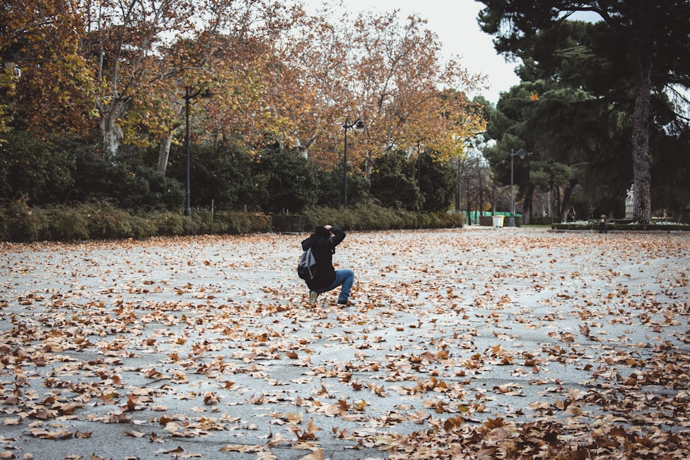 person kneels and takes photo of tree