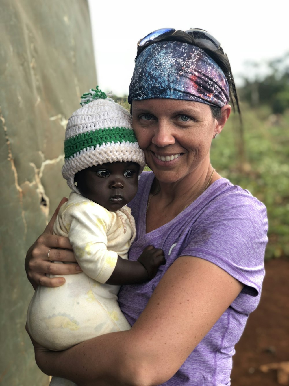 woman carries baby in yellow sleeper