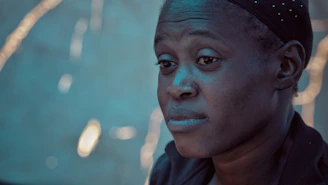 Close-up of a contemplative face illuminated by soft, moody lighting.