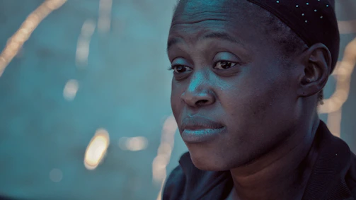 Close-up of a contemplative face illuminated by soft, moody lighting.