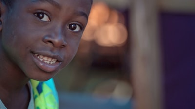 Warm, natural outdoor portrait of a smiling child captured with cinematic lighting effects.