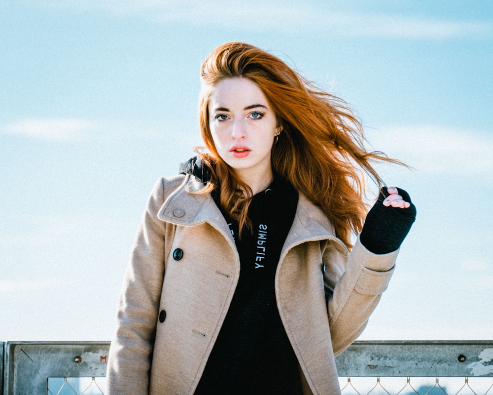 woman wearing brown jacket holding her hair