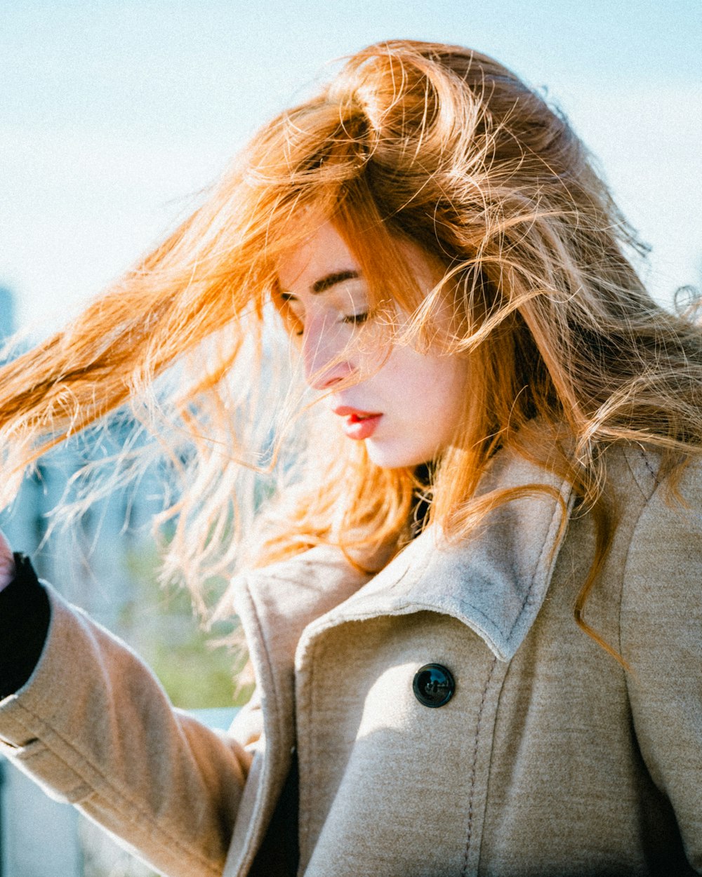 blonde woman in grey coat ssyanding under sunlight