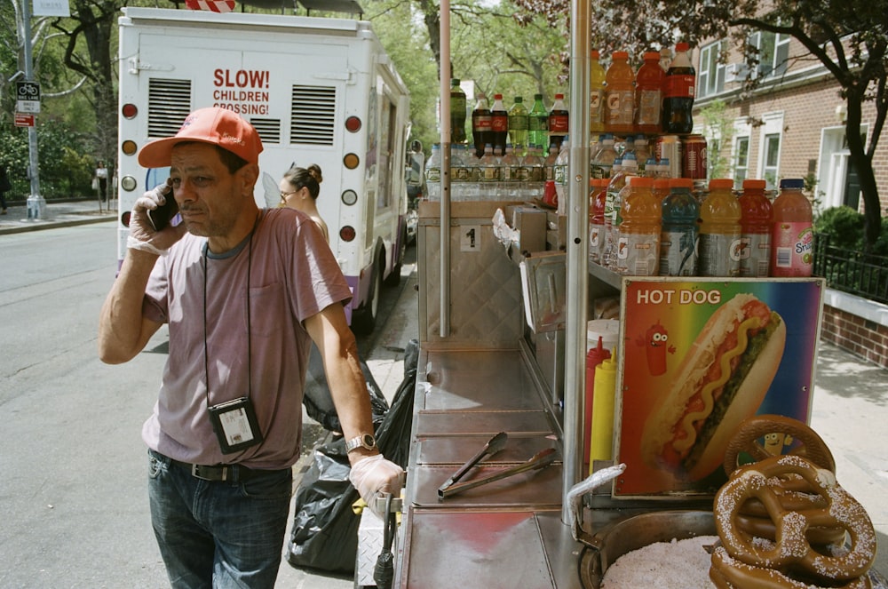 man talking on phone beside food stall