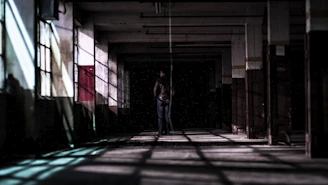 Grainy film shot of a deserted industrial corridor with faint amber lighting.