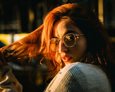Portrait of a non-binary person with colorful hair and expressive eyes, framed by warm sunlight.