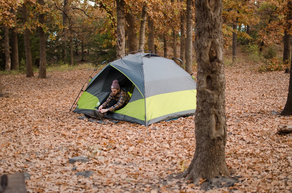 person sitting inside blue and yellow dome tent