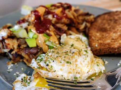 A warm plate of eggs, crispy bacon, and golden hash browns alongside a side of salsa and tortillas.