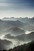 A serene sunrise over misty mountains with a winding road below.