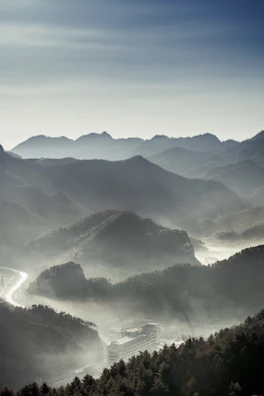 A serene sunrise over misty mountains with a winding road below.