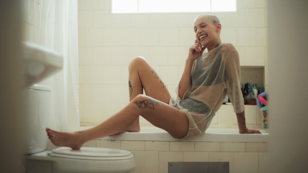 Mujer en vestido de malla sentada en la bañera sonriendo durante el día