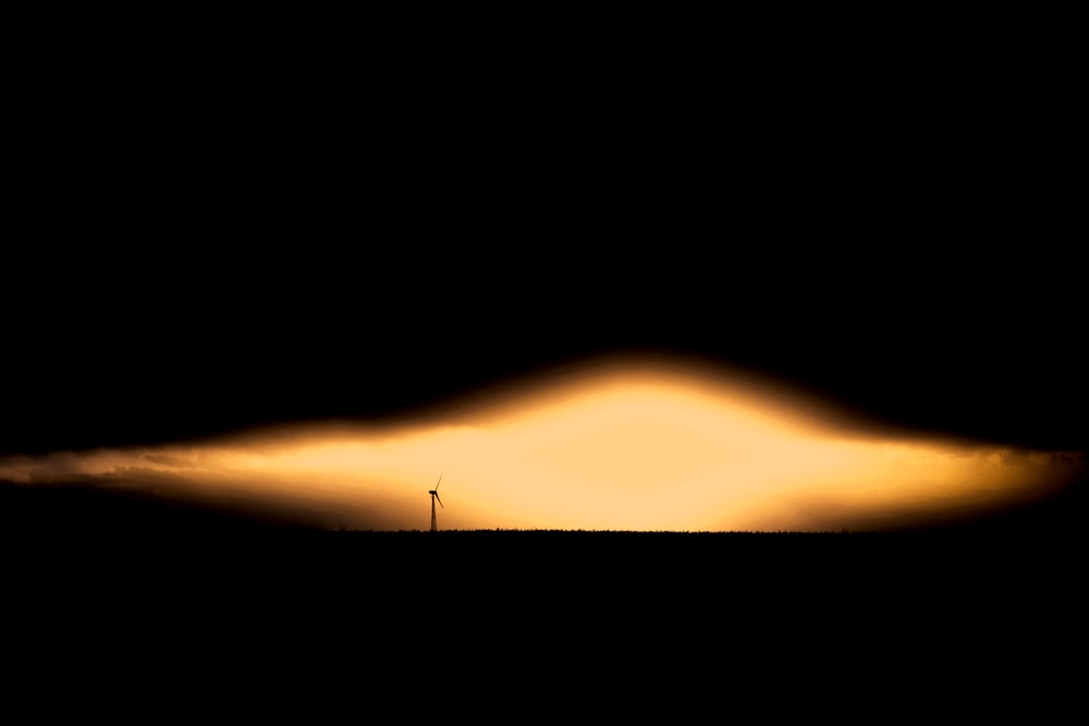 a windmill in the distance with a dark sky in the background