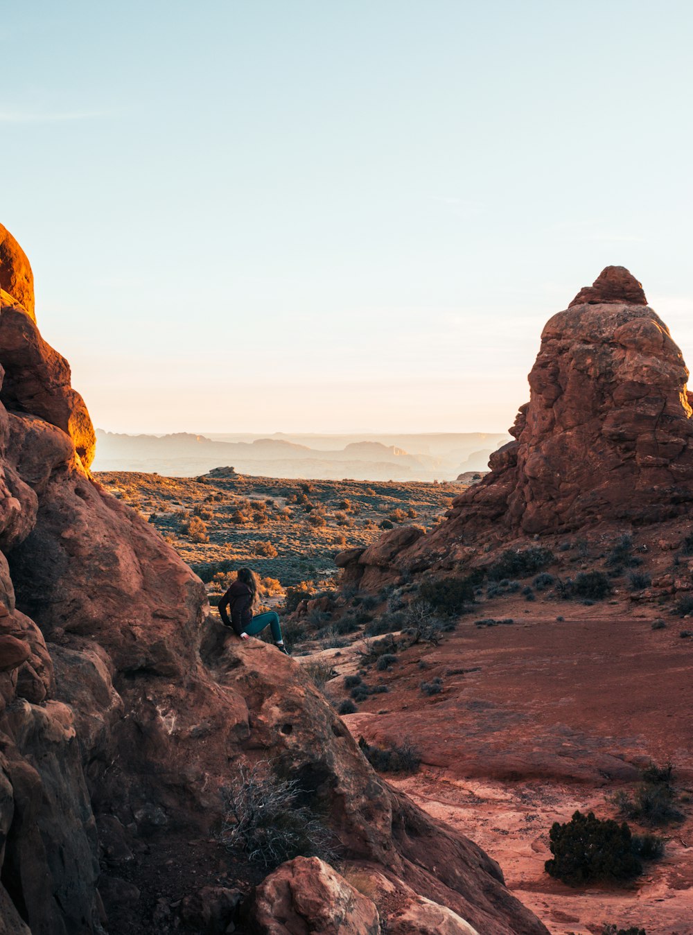 person sitting on rock formations gazing on horizon