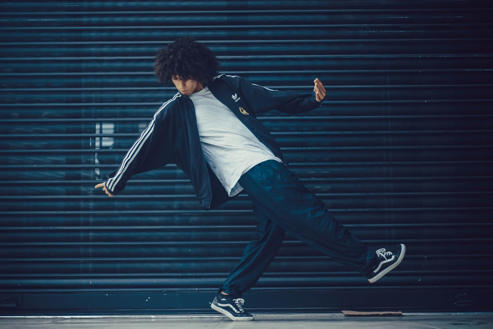 man in tracksuit standing by the black metal pull-up door posing