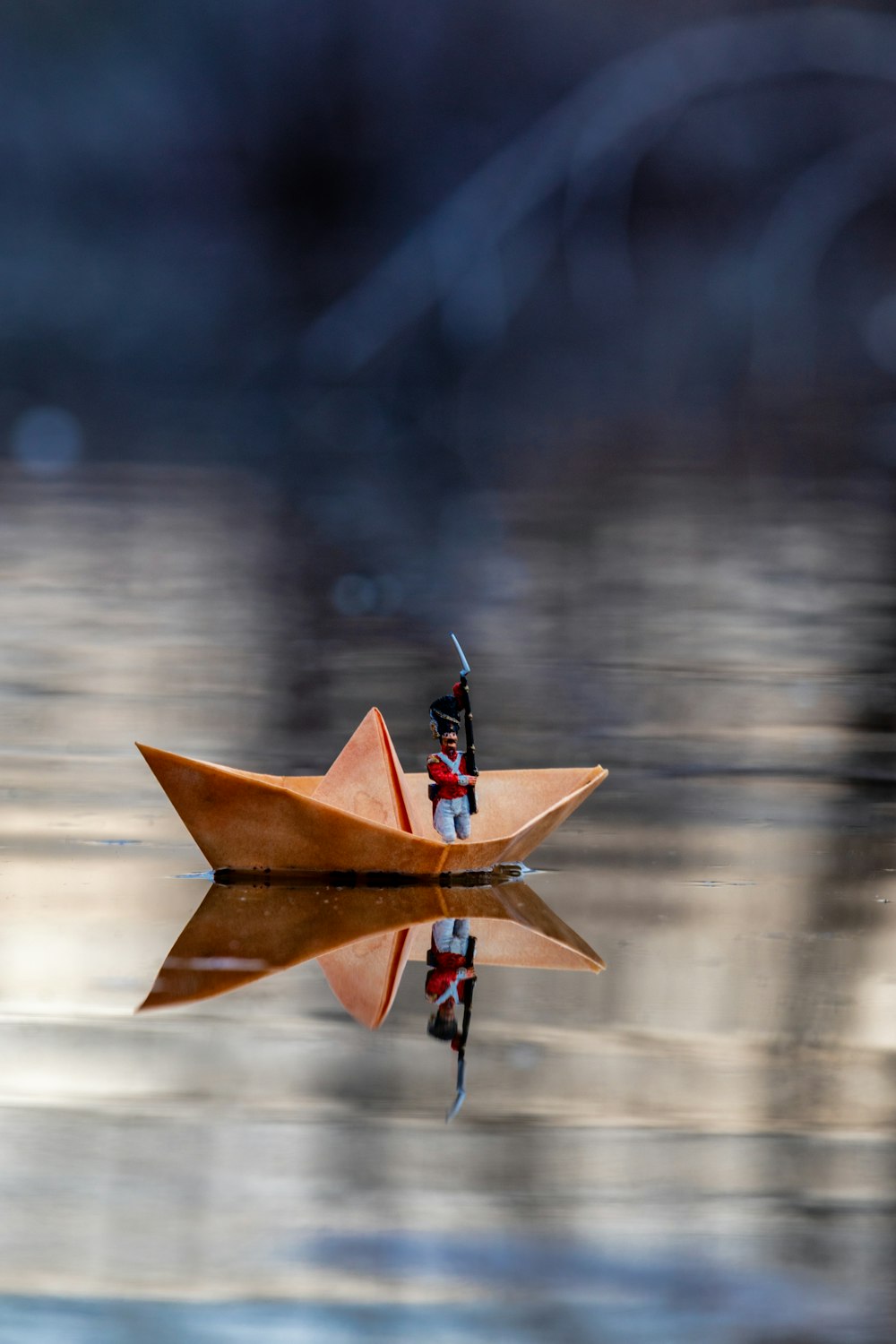 selective focus photography of toy in paper boat on water