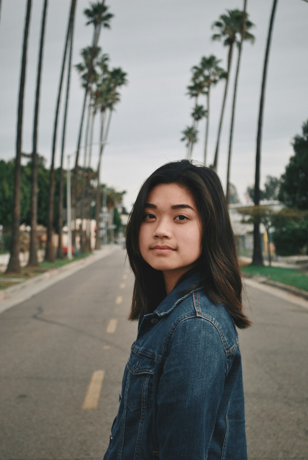 woman in denim jacket standing near trees