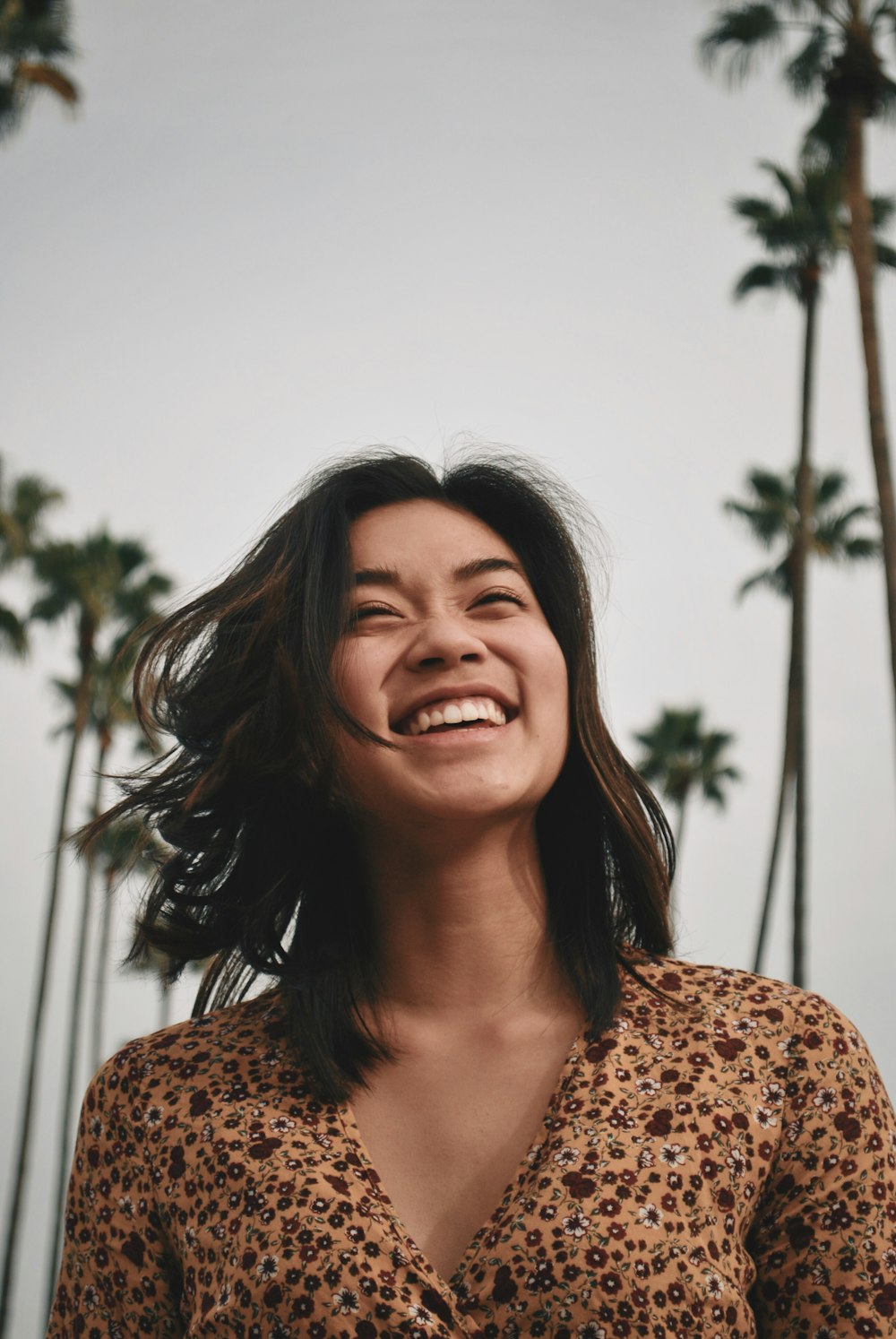 woman in brown floral dress standing and smiling