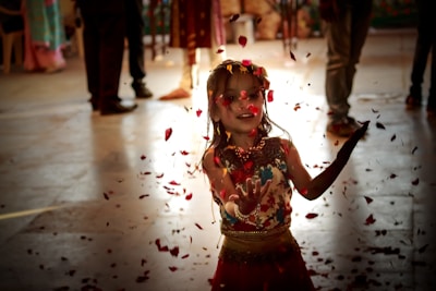A joyful young girl twirling in a vibrant South Indian ethnic dress, surrounded by festive decorations.
