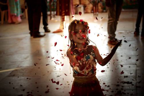 A cheerful little girl twirling in a soft pink kurti with delicate embroidery, surrounded by pastel-colored balloons.
