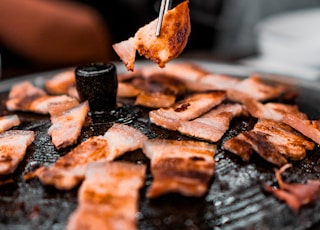 person picking grilled meat from grill using sticks