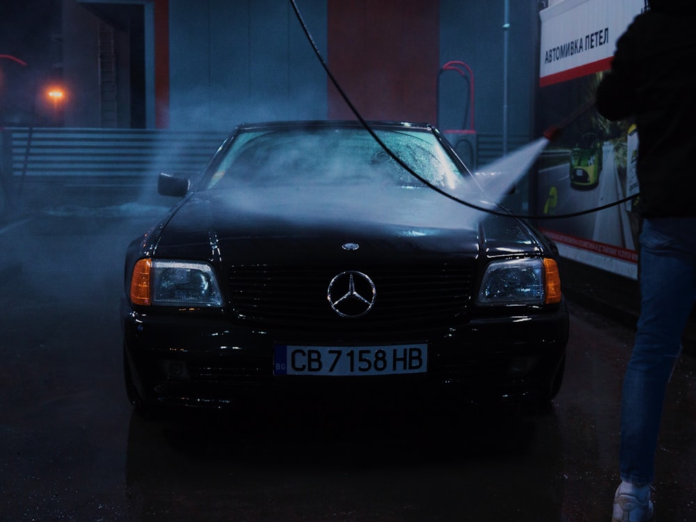 person spraying Mercedes-Benz vehicle with water