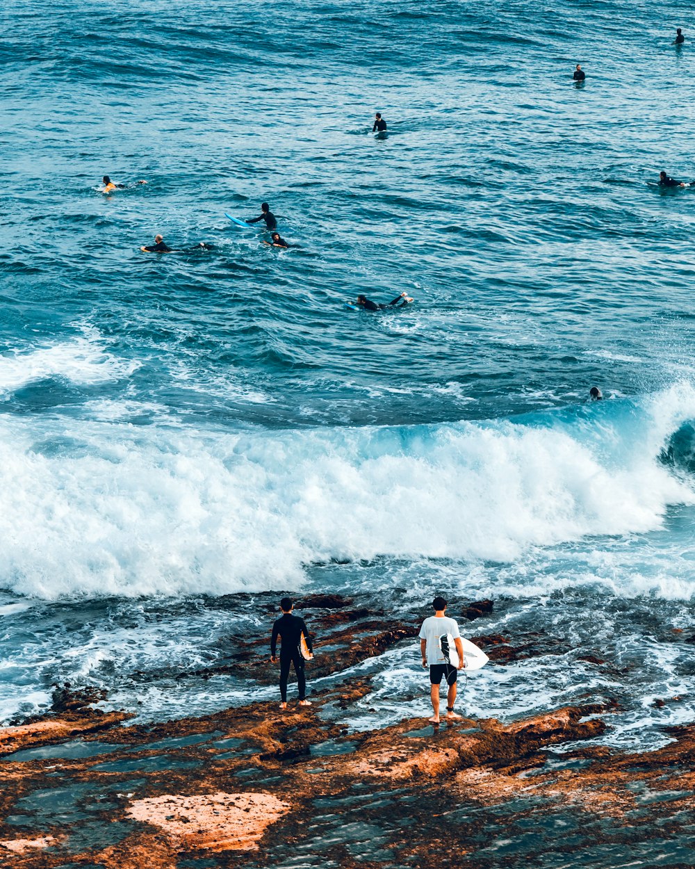 two man carrying surfboard near sea during daytime