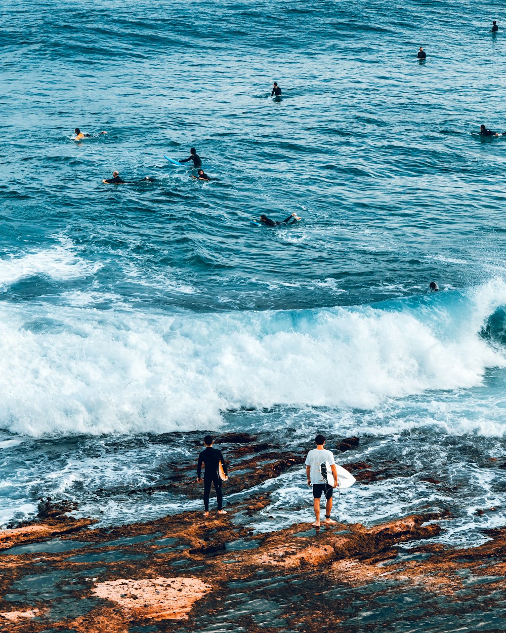 Dos hombres que llevan una tabla de surf cerca del mar durante el día