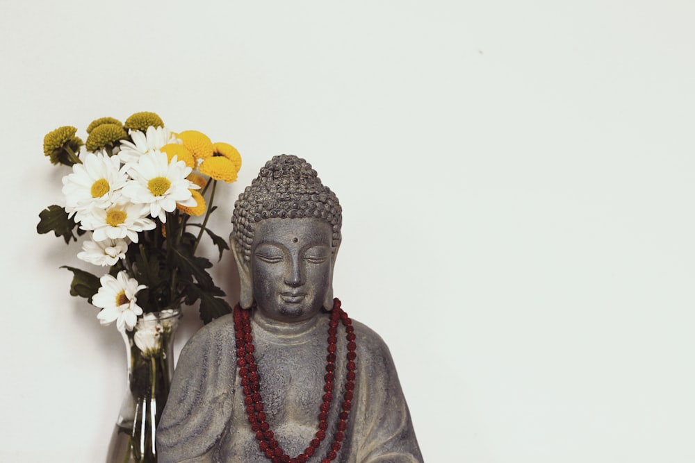 flower in vase near buddha figurine