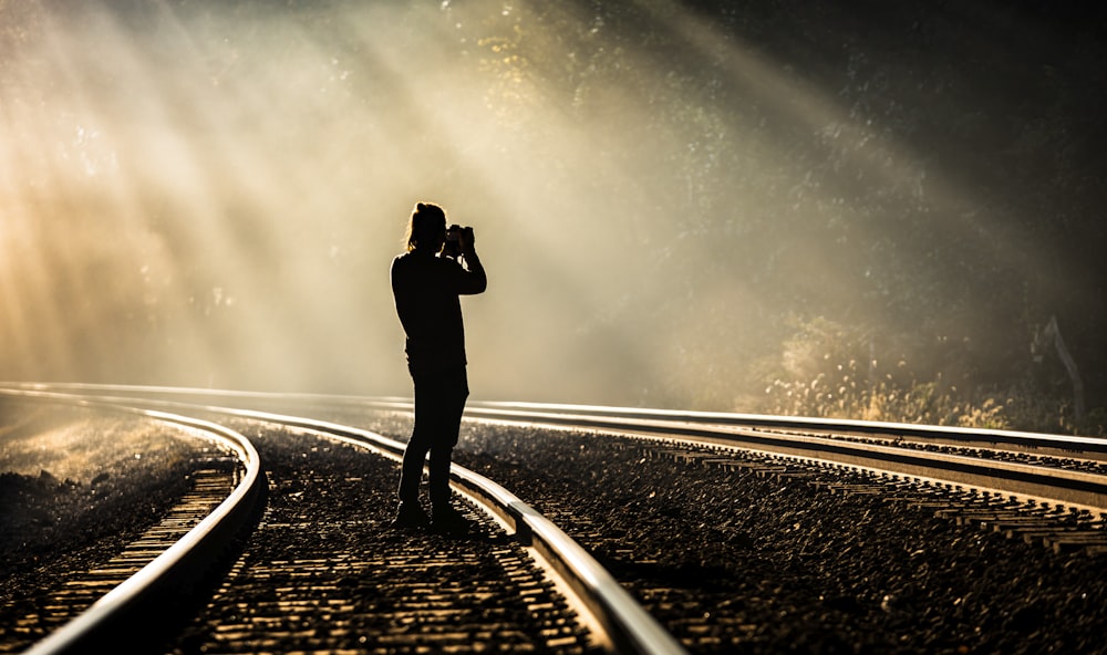 person holding camera standing on train track while taking photo
