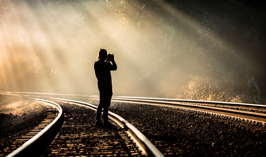 person holding camera standing on train track while taking photo