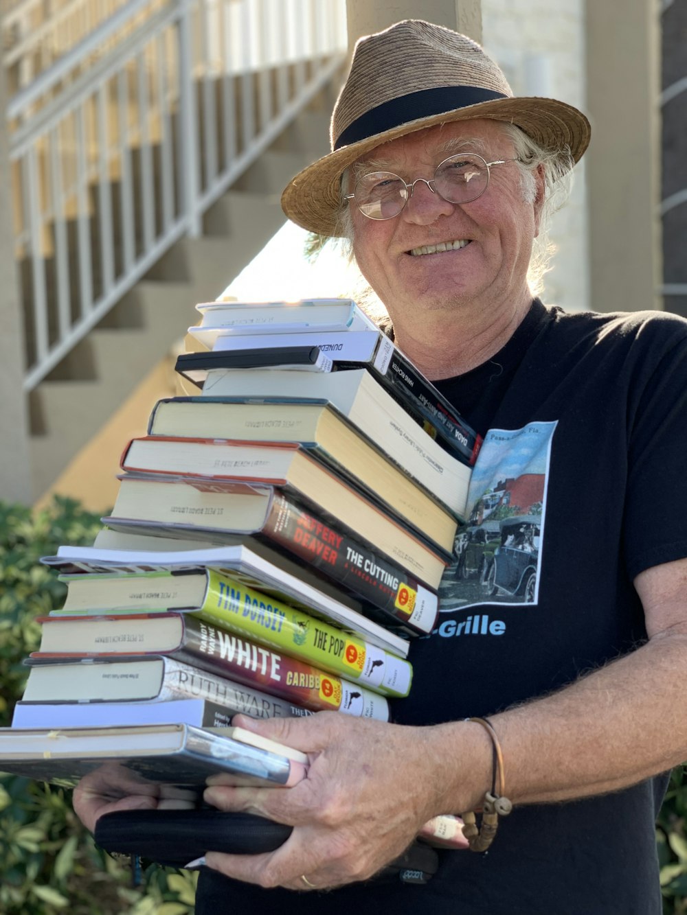 man holding pile of books while smiling