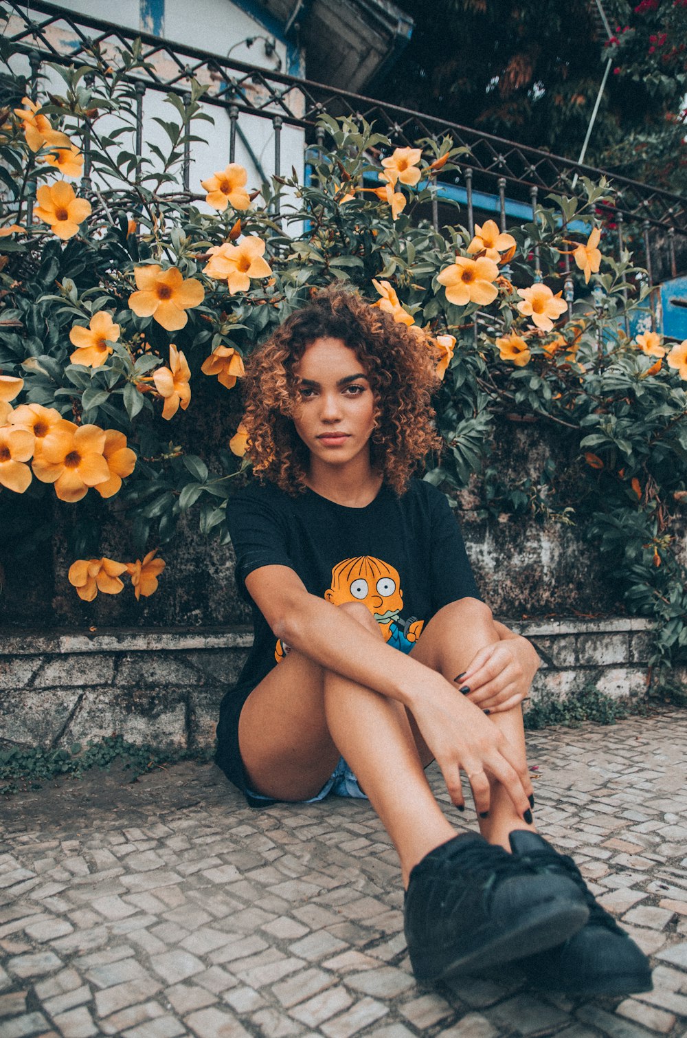 Muchacha sentada en el suelo con la flor detrás durante el día