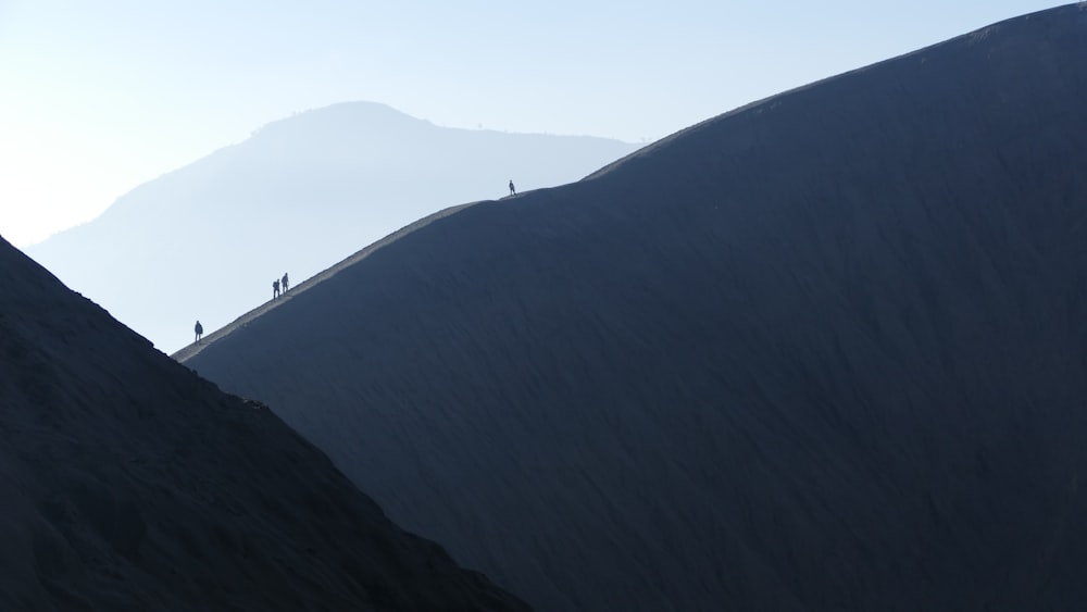silhouette of people walking on mountain during daytime
