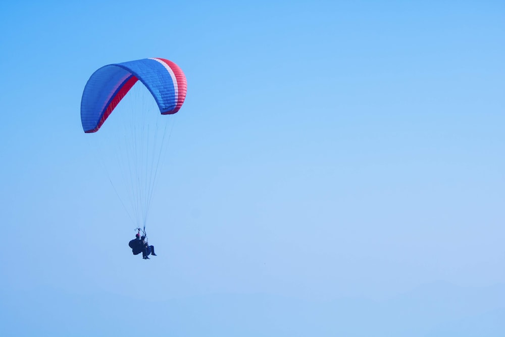 person on parachute under blue sky during daytime