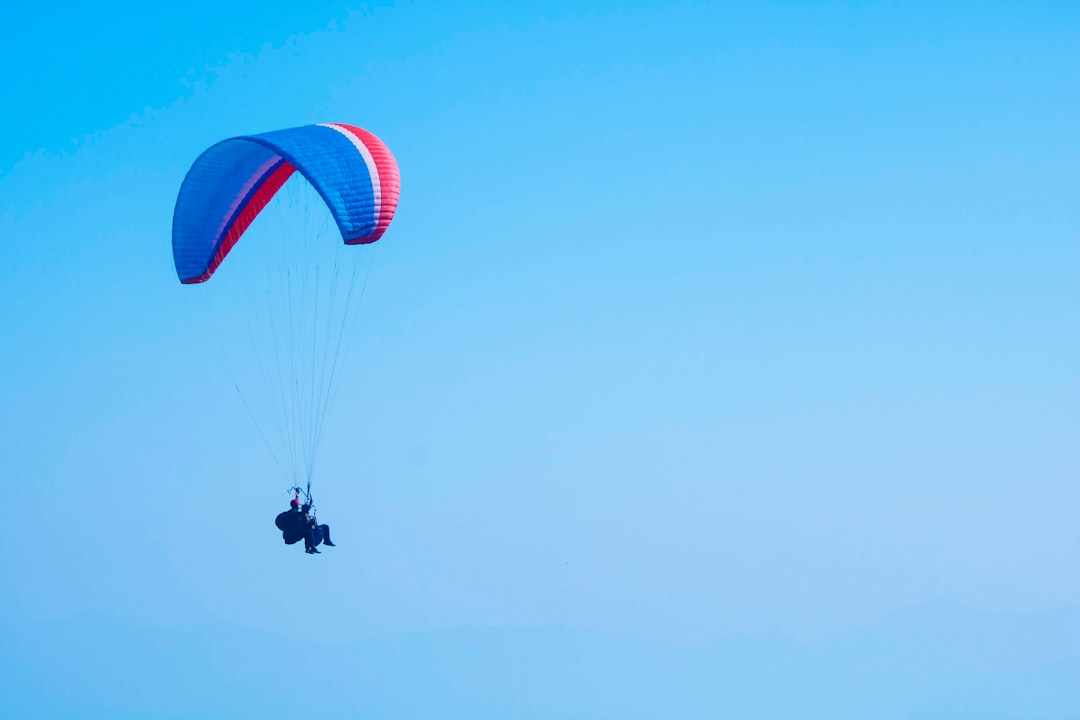 person on parachute under blue sky during daytime