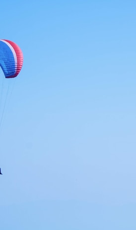 person on parachute under blue sky during daytime