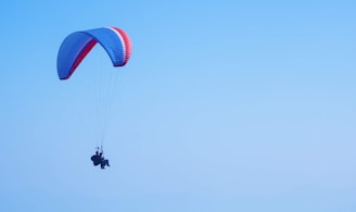 person on parachute under blue sky during daytime