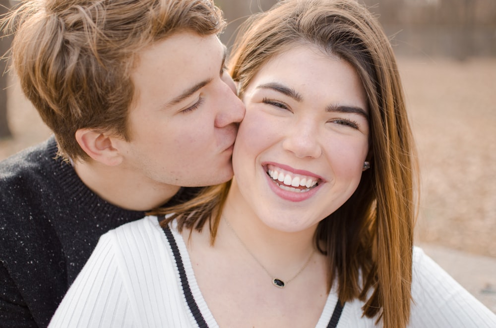 man kissing smiling woman