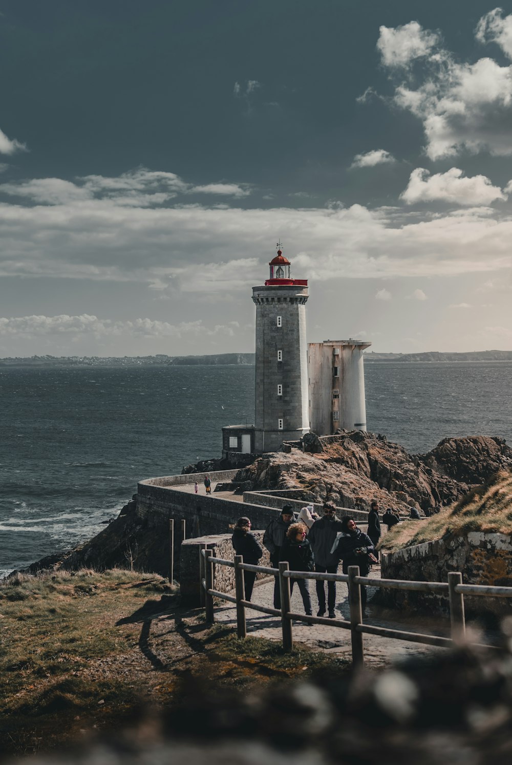 people walking towards gray lighthouse