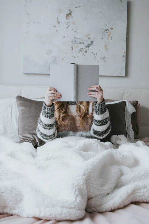 Reading in bed under a blanket